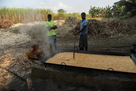 Workers boiling sugarcane juice as they are making Gur (jaggery) in a village on December 10, 2021
