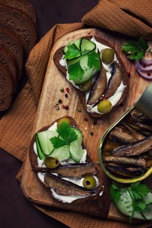 Sandwiches, black bread with sprats, cream cheese, cucumbers, on a cutting board, top view,