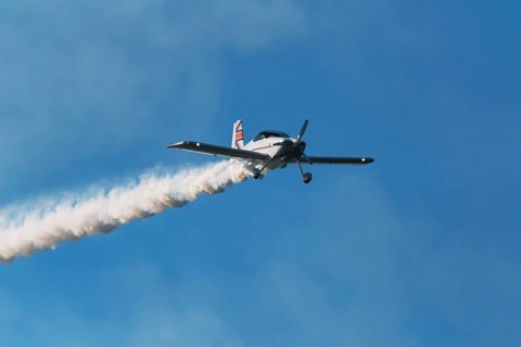 Stunt aerobatic plane performing stunts in blue sky with smoke trail. Concept of speed, difficulty,