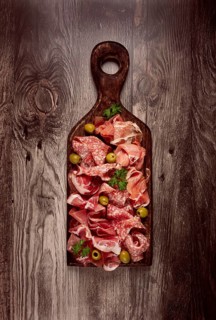 Assortment, sliced meat appetizer, prosciutto, salami and ham, with olives, on a wooden board,