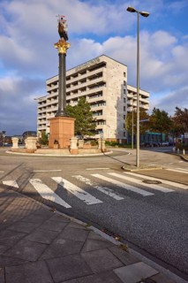 Flat hotel, granite column with metal sculpture of a cog, roundabout between the streets
