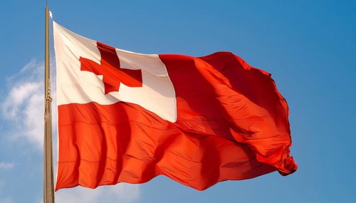 The flag of Tonga, Pacific island state, flutters in the wind, isolated against a blue sky
