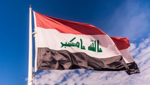 The flag of Iraq flutters in the wind, isolated against a blue sky