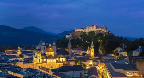 Night view of Salzburg with illuminated historical buildings and the Hohensalzburg Fortress in the