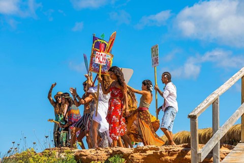 Colourfully dressed youths with musical instruments and banners form a love parade and promote the