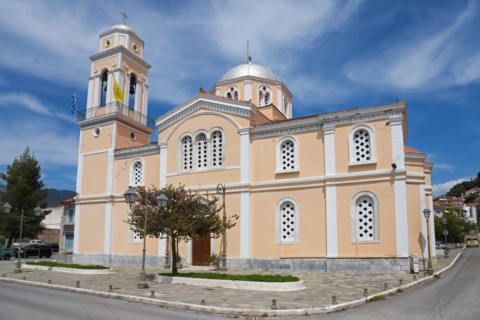 Neoclassical church with pink façade on a street corner, Greek flag flying, Church of Agios