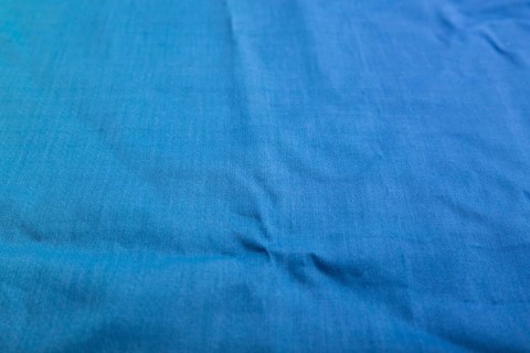 Fragment of smooth cotton blue tissue. Side view, natural textile background and texture