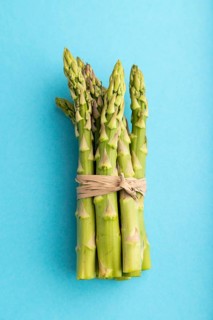 Bunch of fresh green asparagus on blue pastel background. Top view, flat lay, close up. harvest,