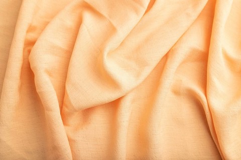 Fragment of orange linen tissue. Top view, natural textile background and texture. wave concept,