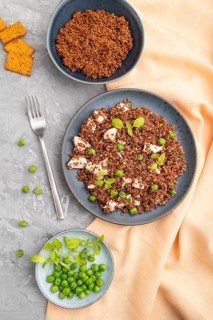 Quinoa porridge with green pea and chicken on ceramic plate on a gray concrete background and
