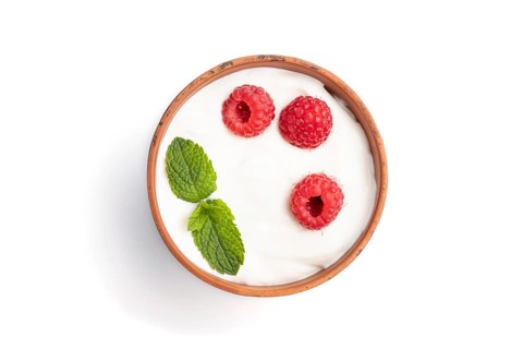 Yogurt with raspberry in clay cup isolated on white background. top view, flat lay, close up