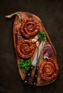 Fried spiral sausages, on a wooden board, top view, with spices, no people