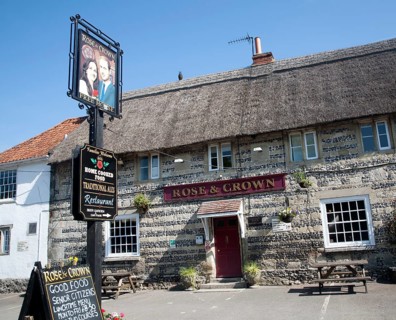 Rose and Crown pub at Tilshead, Wiltshire, England with pub sign painted of Prince William and his