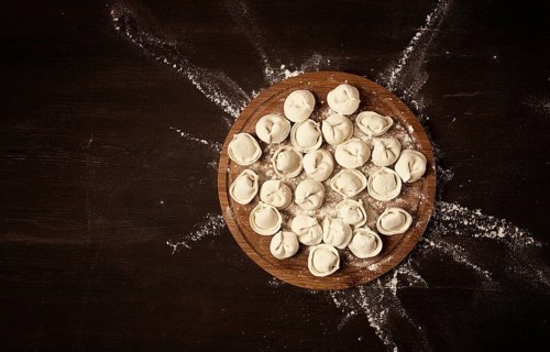 Raw frozen dumplings, on a wooden board, top view, horizontal, rustic style, no people