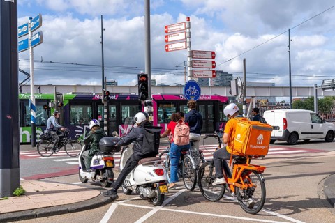 Cyclist, moped rider, waiting at a red traffic light, Feijenoord, in front of the Erasmus Bridge,
