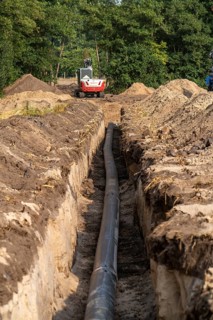 Laying of district heating pipes, next to a field, with maize, the district heating comes from a