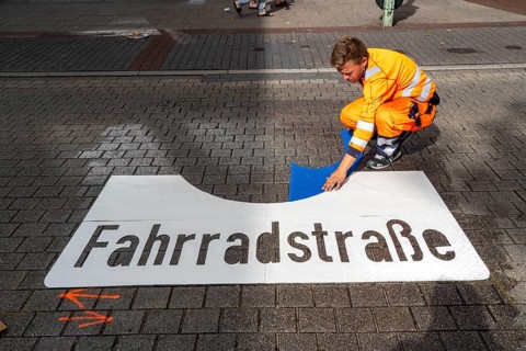 Application of road markings for a cycle lane, Rüttenscheider Straße in Essen, in the shopping and