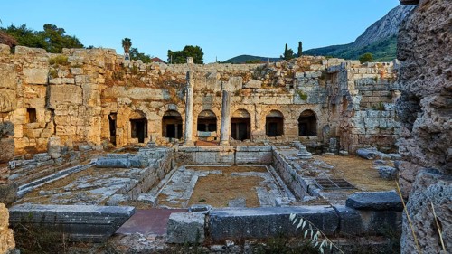 Courtyard of ancient ruins with columns and a clear sky in the background, Peirene Fountain,