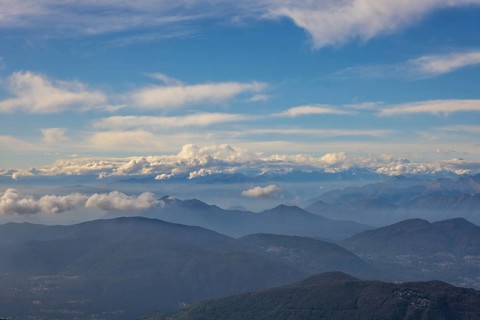 Aerial View over a Beautiful Mountainscape and And Snow Capped Mountain and with Floating Clouds in