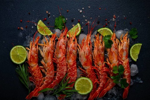 Langoustines, Australian, freshly frozen on ice, top view, lime and greens