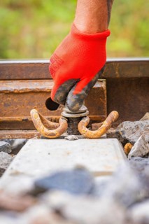 Close-up of a red-gloved hand working on a tool on rails, track construction, Hermann Hessebahn,