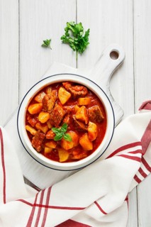 Potatoes stewed with meat, in tomato sauce, with spices and herbs, no people, on a white table