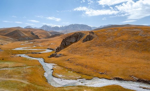 River Kol Suu winds through a mountain valley with hills of yellow grass, Naryn Province,