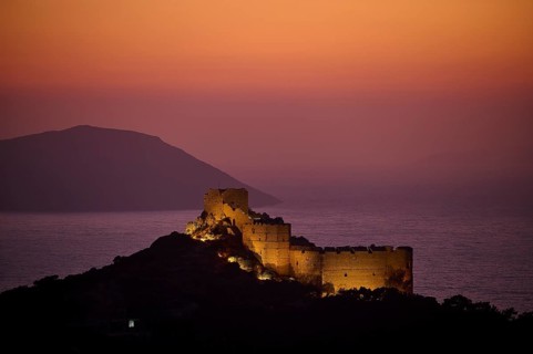 Illuminated castle ruins at dusk with a view of the sea and the surrounding mountains, Kritinia