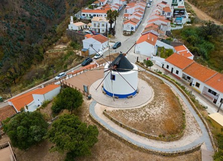 Aerial view of a village with a central windmill surrounded by houses with orange-coloured roofs,