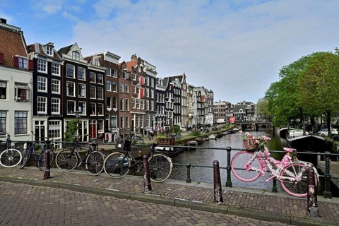 Pink bicycle decorated with flowers on a bridge by a canal, Amsterdam, Province of North Holland,