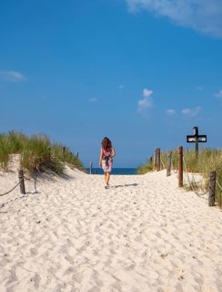 Woman in colourful dress on empty beach, Slovincian National Park, Slowinski Park Narodowy, Poland,