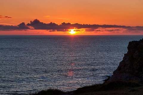 Sunset behind clouds on the Atlantic Ocean, rocky coast Pointe du Van, backlight, Cap Sizun