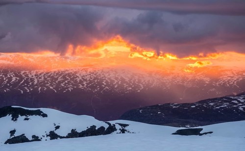 Sunset, clouds in backlight over snow covered mountains, view from top of Fannaråken, Jotunheimen