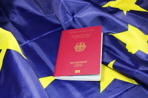 Symbolic image of freedom to travel: German passport on a European flag