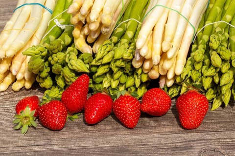 Green asparagus, white asparagus and fresh strawberries decorated on a rustic wooden table