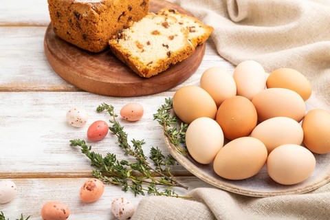 Homemade easter pie with raisins and eggs on plate on a white wooden background and linen textile.