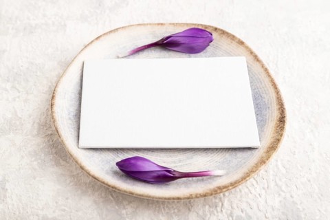 White paper invitation card, mockup with crocus flowers on ceramic plate and gray concrete