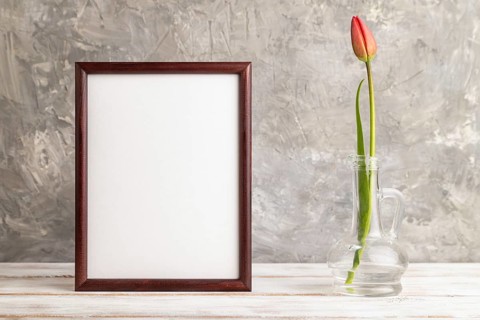 Wooden frame with red tulip flower in glass on gray concrete background. side view, copy space,