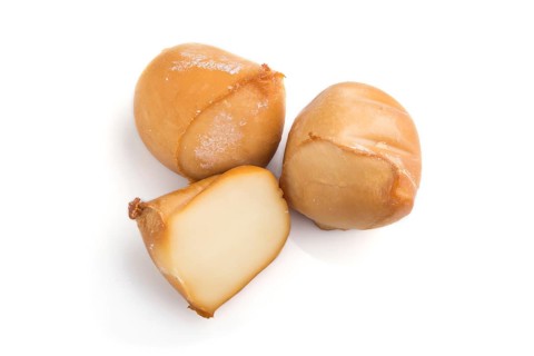 Piece of smoked cheese isolated on white background. Side view, close up