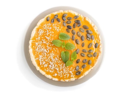 Traditional american sweet pumpkin pie decorated with mint, sesame and pumpkin seeds isolated