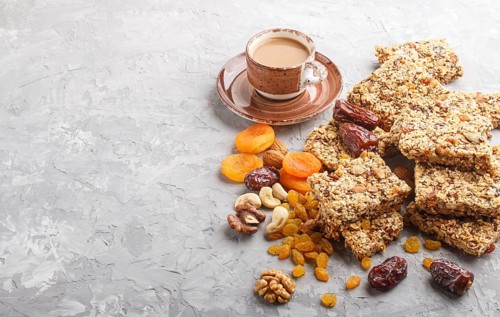 Homemade granola from oat flakes, dates, dried apricots, raisins, nuts with a cup of coffee on a