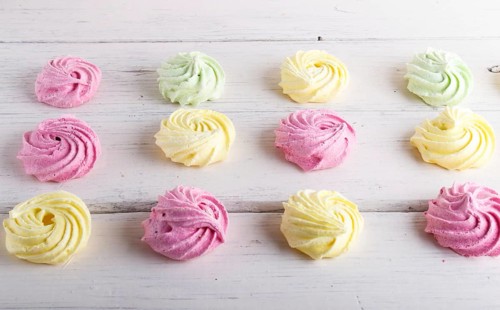 Set of colored meringues on white wooden background. top view, flat lay. geometric pattern