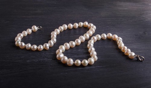 Caramel colored pearl beads on a black background. top view, close up