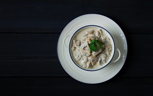 Cream sauce with mushrooms, top view, on a dark gray wooden table, horizontal, no people