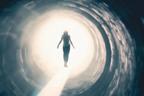 A woman floats through a tunnel into the light, symbolic image for near-death experience, death,