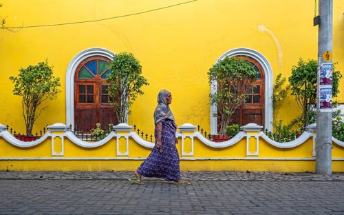 Street scene with Indian woman in front of yellow house, Fort Kochi, Cochin, Kerala, India, Asia