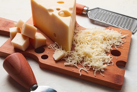 Grated cheese, Maasdam, on a cutting board, grater and cheese knife, close-up, no people