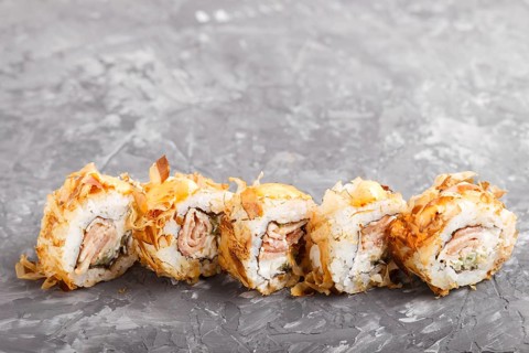 Japanese maki sushi rolls with tuna, cucumber, cheese on black concrete background. Side view,