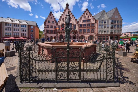 Fountain of Justice and Römer Town Hall on the Römerberg under a blue sky with cumulus clouds in