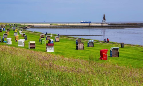Grassy beach on the dyke with beach chairs and landmark Kugelbake in the district of Grimmershörn,